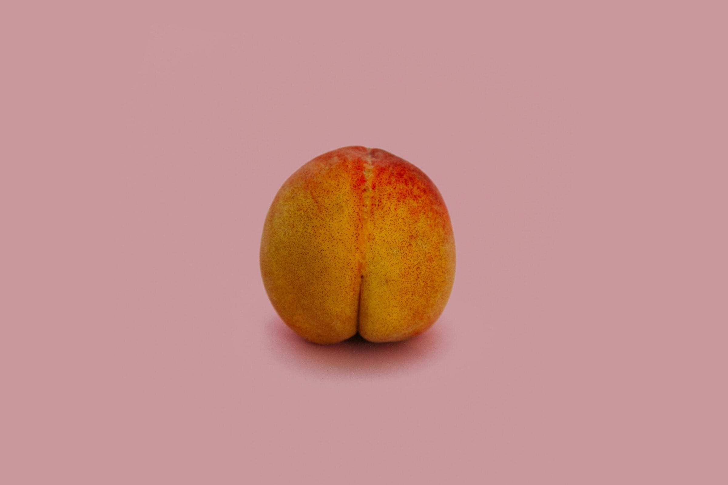 Close-up of peach against pink backdrop