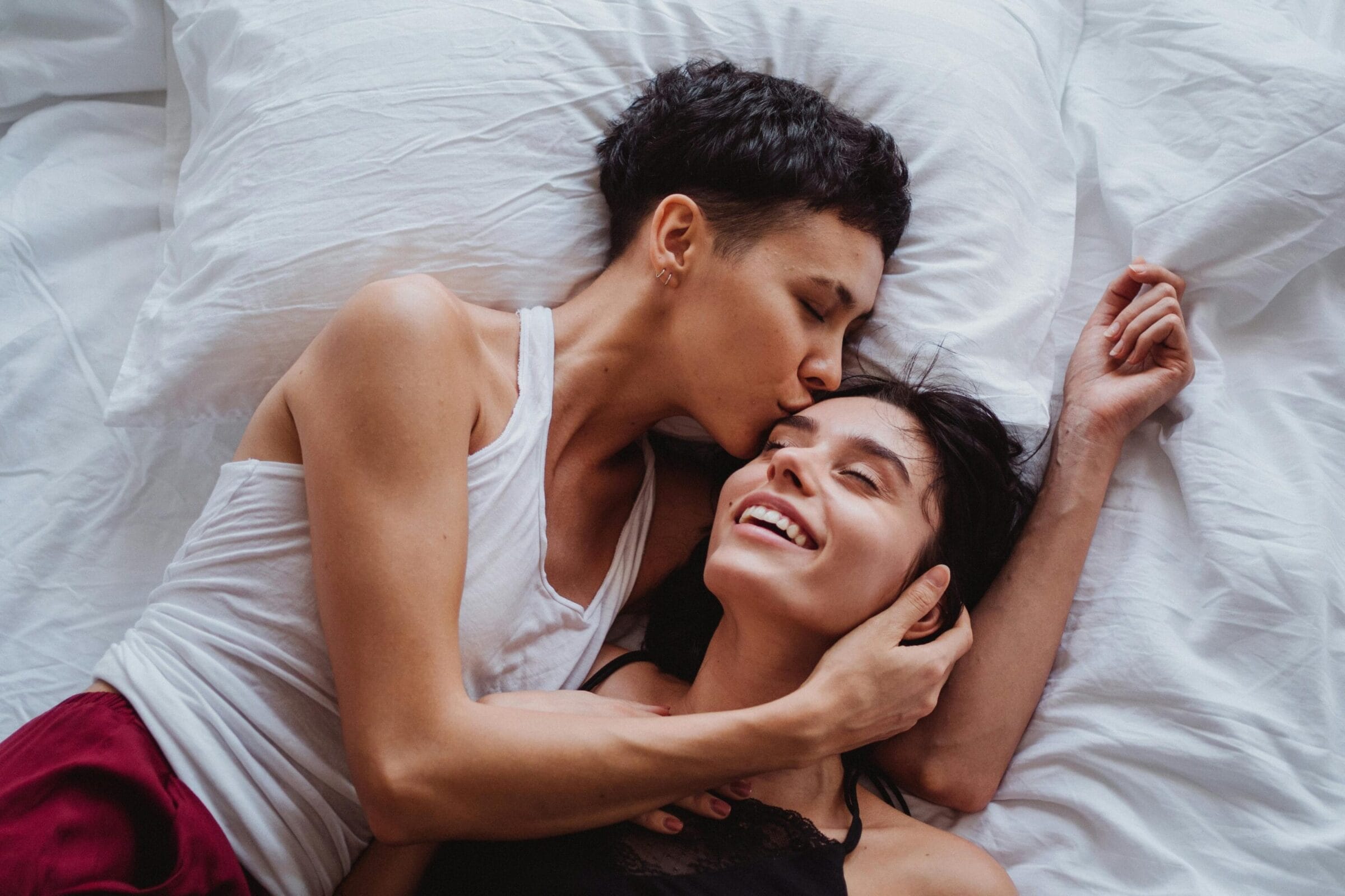 Female couple embracing intimately in bed
