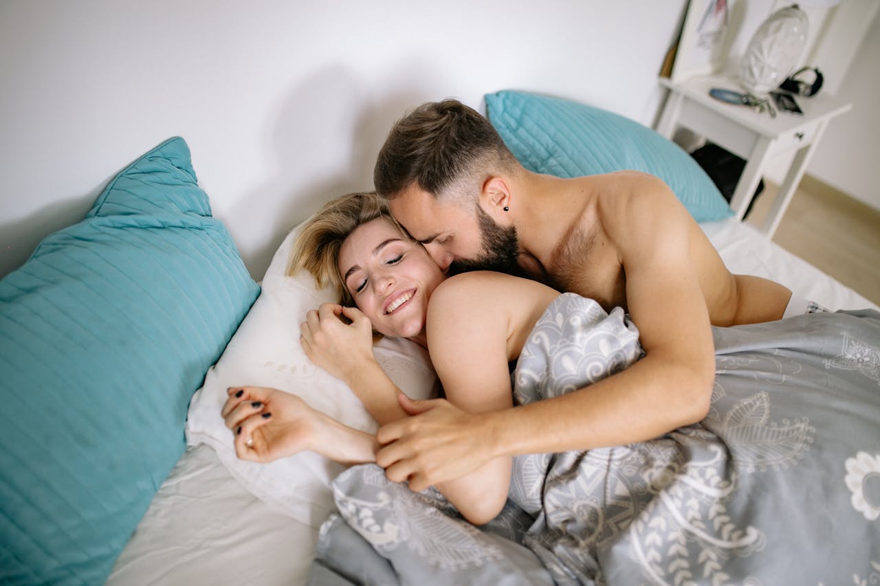 Smiling man and woman spooning in bed