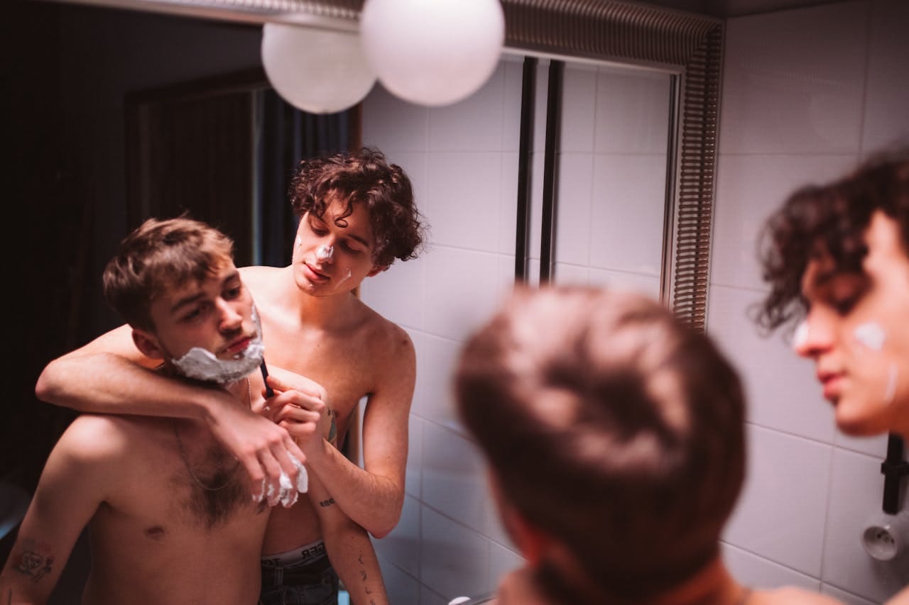Couple shaving in front of bathroom mirror