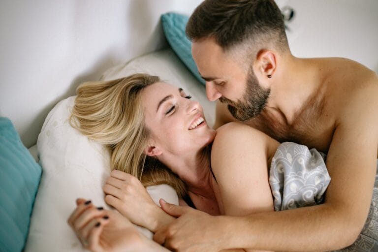 Smiling blonde woman and brunette man laying in bed
